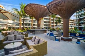an outdoor patio with tables and chairs and umbrellas at Sunshine Layan Beach Resort studio #84191 in Layan Beach