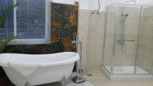 a bathroom with a shower and a bath tub at Tea Hills Bungalow in Hatton