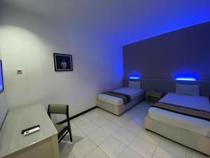 a room with two beds and a desk with blue lights at Kharisma Hotel in Madiun +145 photos