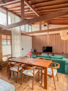 Japanese Villa في كوتا لومبوك: غرفة معيشة مع طاولة خشبية وأريكة خضراء