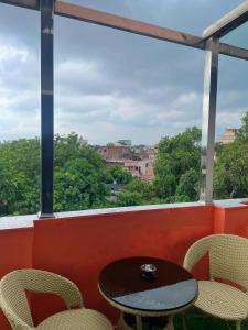 Una mesa y sillas en un balcón con vista. en VIA VARANASI - A Boutique Hotel at Assi Ghat, en Varanasi