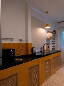 eine Küche mit schwarzer Arbeitsplatte und Mikrowelle in der Unterkunft Bamboo House in Laguna Phuket + 10 Fotos