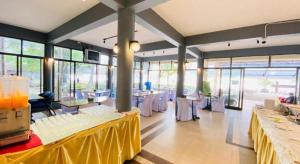 una sala da pranzo con tavoli, sedie e finestre di Alongkot Beach Resort Khanom a Ban Phang Phrao