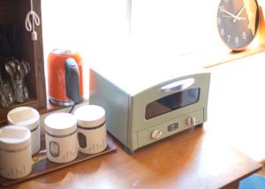 a toaster oven and some cups on a shelf at The Pax Hostel in Osaka