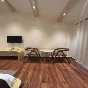 a room with two chairs and a table and a tv at Evaan Litchi Orchards and Resorts, Corbett in Rāmnagar