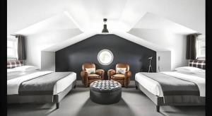 a bedroom with two beds and two chairs and a window at The George Montclair in Montclair