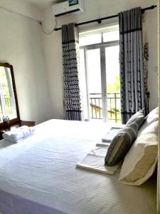 ein Schlafzimmer mit einem großen weißen Bett mit einem Fenster in der Unterkunft Hagiazo Guest Inn Mirissa in Telangapata