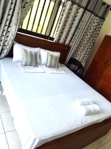 ein großes Bett mit weißen Laken und Kissen in der Unterkunft Hagiazo Guest Inn Mirissa in Telangapata