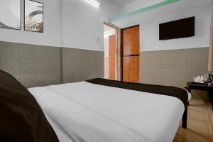 una camera da letto con un letto bianco e una televisione di Hotel O Calangute Beach Road Formerly Crystal Holiday Homes a Calangute Altre 22 foto