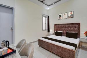 a bedroom with a large bed and chairs in it at Hotel O Meerut Central College Formerly Saffron in Meerut