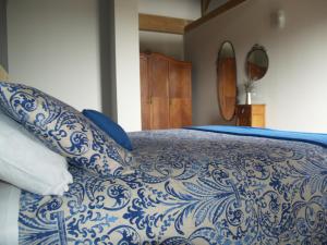 a bed with blue and white sheets and pillows at Etxekone in Guernica y Luno