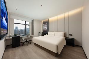 a bedroom with a bed and a desk and a tv at Atour Hotel Shanghai Wujiaochang Wanda Plaza in Shanghai