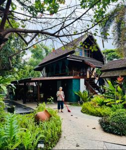 a woman standing in front of a house with a broom at Sala Homestay in Ban Mae Nai +45 photos
