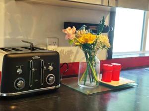a toaster and a vase of flowers on a counter at Peaceful Home Near Gardens, University & Downtown in Hamilton
