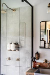 a bathroom with a shower with a sink and a mirror at Riverfront Luxury Stay Tiny House Sauna and Bath in Old Bar