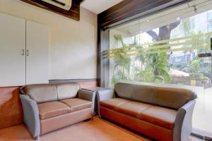 a leather couch in a room with a large window at Super Townhouse Andheri Sakinaka Metro Formerly Hotel Amour in Mumbai
