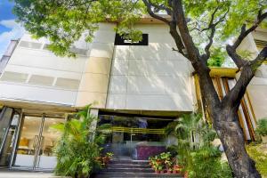 a white building with a tree in front of it at Super Townhouse Andheri Sakinaka Metro Formerly Hotel Amour in Mumbai