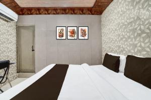 a bedroom with a white bed with three pictures on the wall at Super Hotel O Hindon Airport Ghaziabad in Ghaziabad +21 photos