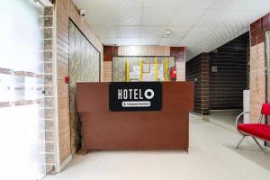 a hotel lobby with a red chair and a sign at Super Hotel O Hindon Airport Ghaziabad in Ghaziabad
