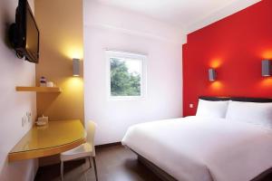 una camera da letto con un letto bianco e una parete rossa di Amaris Hotel Pakuan Bogor a Bogor