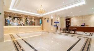 哈尔滨Vienna Hotel Harbin Central Avenue的宽敞的大厅里有一张桌子，墙上挂着一幅画 更多125张照片