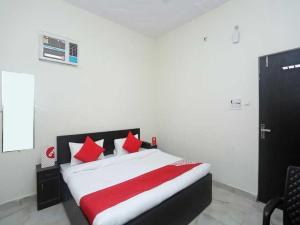 Un dormitorio con una cama con almohadas rojas y blancas. en Hotel O Rajiv Gandhi Bus Stop Bangalore Formerly Maharaja, en Jālahalli