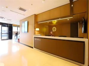 天津IU Hotel Tianjin Tianta Scenic Spot Wujiayao Metro Station的一名男子坐在大厅的柜台前