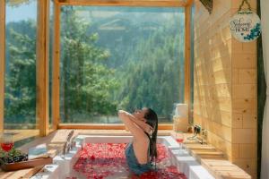 a woman sitting in a bath tub with a window at Skyview Jacuzzi Treehouse Power Backup Tandi in Kulu