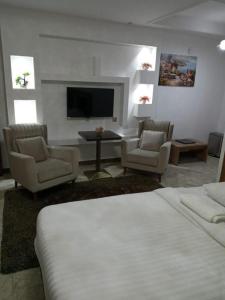 ein Schlafzimmer mit einem Bett und zwei Stühlen und einem Fernseher in der Unterkunft Nermeam in Muscat