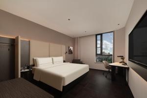 ein Schlafzimmer mit einem weißen Bett und einem Fernseher in der Unterkunft Atour Hotel Shanghai The Bund Yuyuan Subway Station in Shanghai