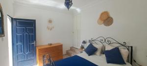 a bedroom with a bed with blue pillows and a blue door at Riad Diaz Taghazout in Taghazout
