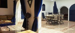 a living room with a table and chairs and blue curtains at Riad Diaz Taghazout in Taghazout +16 photos