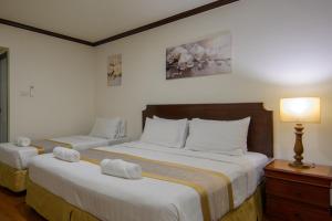 a bedroom with two beds with towels on them at The Victory Residences Bangkok in Bangkok