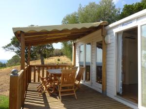 a patio with a table and chairs on a deck at Camping Mozziconaccio in Sainte-Lucie de Porto-Vecchio