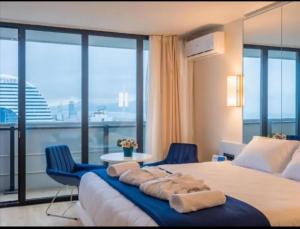 ORBI CITY - Luxury Prestige Hotel في باتومي: غرفة نوم بسرير كبير مع كرسيين ازرق +50 صورة