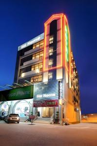 a tall building with a neon sign in front of it at Inn Home Hotel Muar in Kampung Tanjung Agas