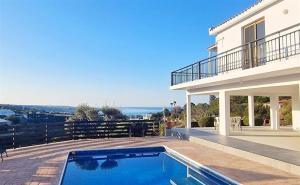 a villa with a swimming pool in front of a house at Serene Serenity in Paphos