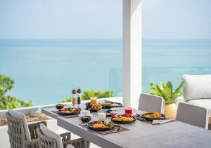 a table with plates of food on a balcony at Cape Azure Resort Samui by Thalsea in Plai Laem +94 photos