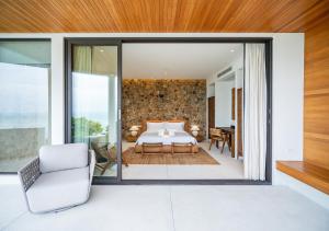 una camera da letto con un letto e una parete di vetro di Cape Azure Resort Samui by Thalsea a Plai Laem Altre 99 foto