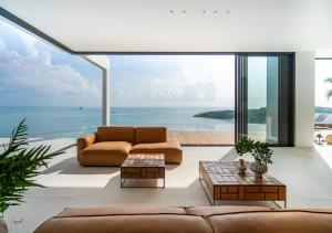 a living room with a couch and a view of the ocean at Cape Azure Resort Samui by Thalsea in Plai Laem