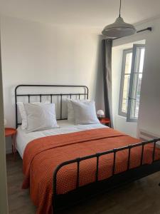 a bed with an orange blanket and white pillows at Maison Mado in La Chaize-Giraud