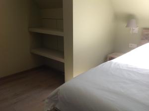 a bedroom with a white bed and shelves at Kokkelikoo in Blankenberge