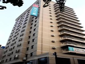 ein hohes Gebäude mit blauem Schild drauf in der Unterkunft Jinjiang Inn Zhenjiang Jiangsu University Suning Plaza in Zhenjiang