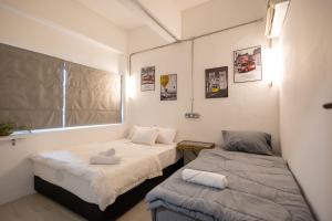 two twin beds in a room with a window at Kenny Hill Boutique Hotel near Borneo Medical Centre Kuching in Kuching