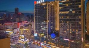 vista di un alto edificio in una città di notte di 7Days Premium Chongqing Jiangbei International Airport Rongchuang a Chongqing