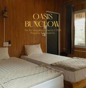 two beds in a room with a sign on the wall at Catba Oasis Bungalows in Cat Ba