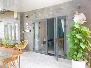 a patio with glass doors and a table and a plant at Nghi Homestay Phan Rang in Bắc Sớn