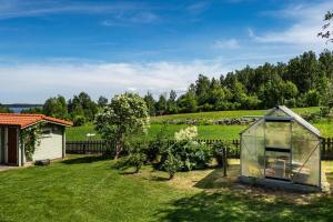 a small greenhouse in a garden next to a house at Unique Mongolian Yurt near lake together with guest house in Hjo