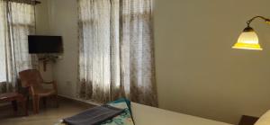 a room with a table and a lamp and curtains at East Home Stay in Dharmsala