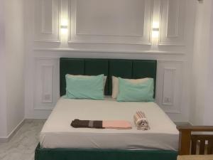 a bed with a green head board and two pillows at Elysian Home Villa in Madiwala